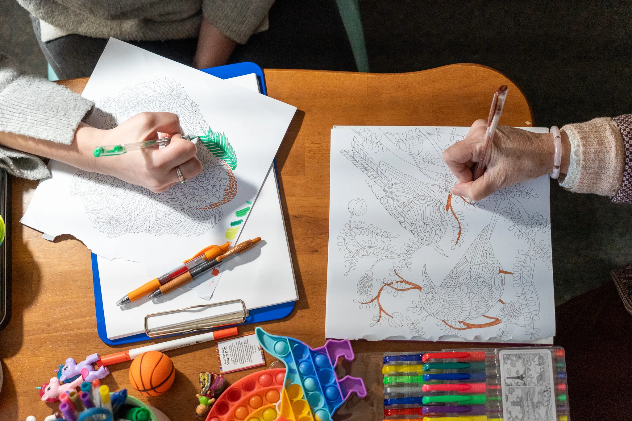Joan and a client's hands each coloring.
